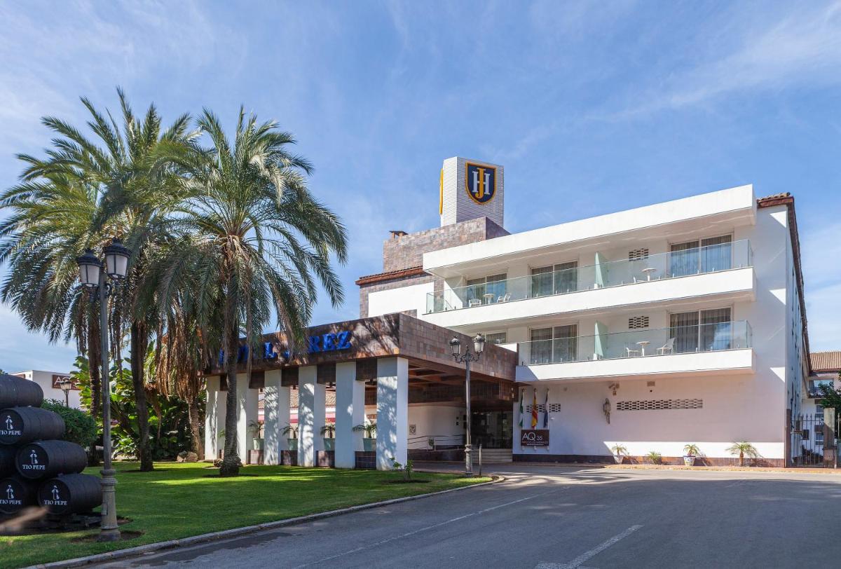Un gran edificio blanco con palmeras delante. en Hotel Jerez & Spa, en Jerez de la Frontera
