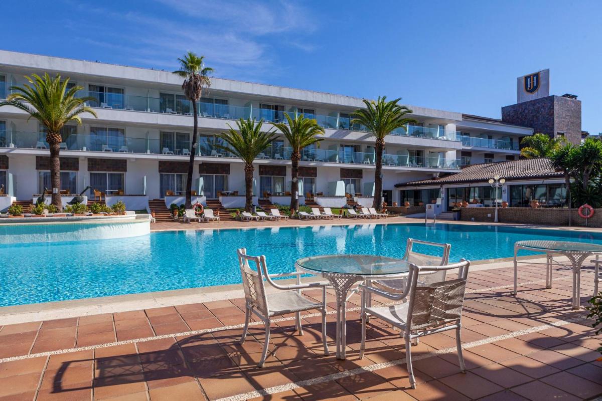 Una piscina con mesas y sillas frente a un edificio. en Hotel Jerez & Spa, en Jerez de la Frontera