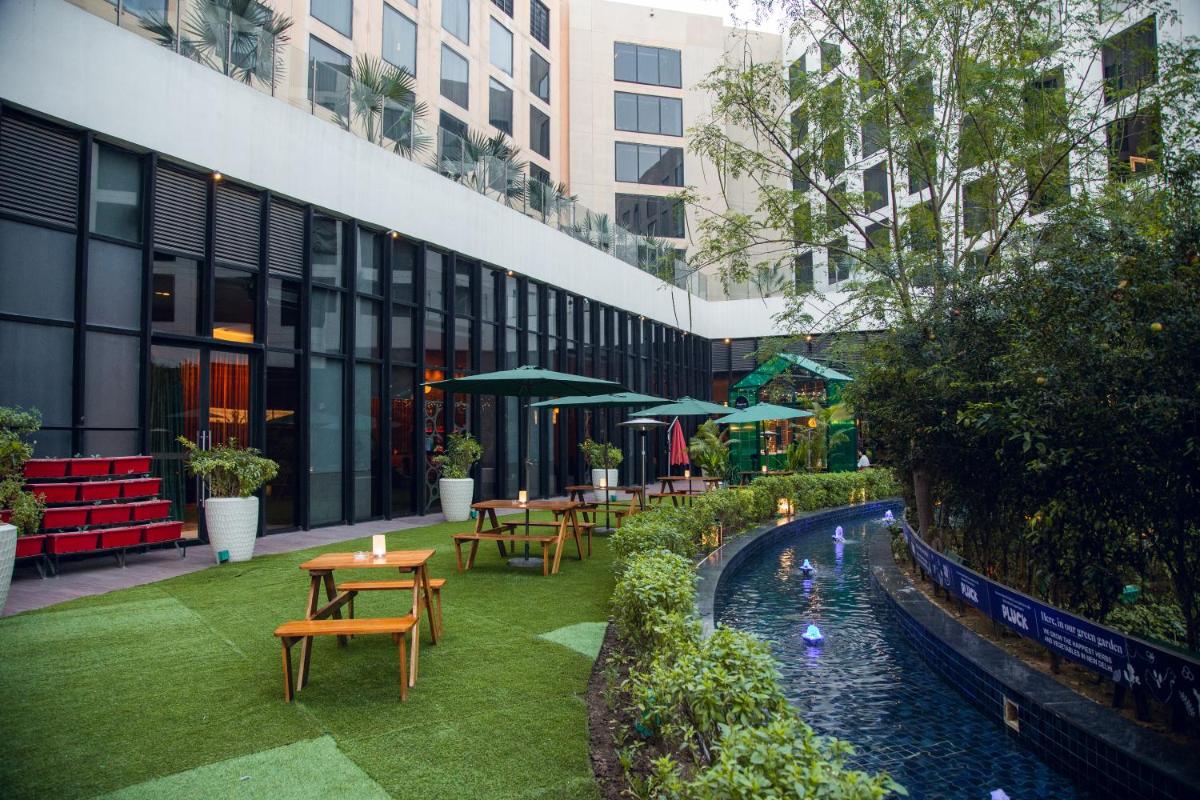 a courtyard with tables and chairs and a pool at Novotel New Delhi Aerocity in New Delhi