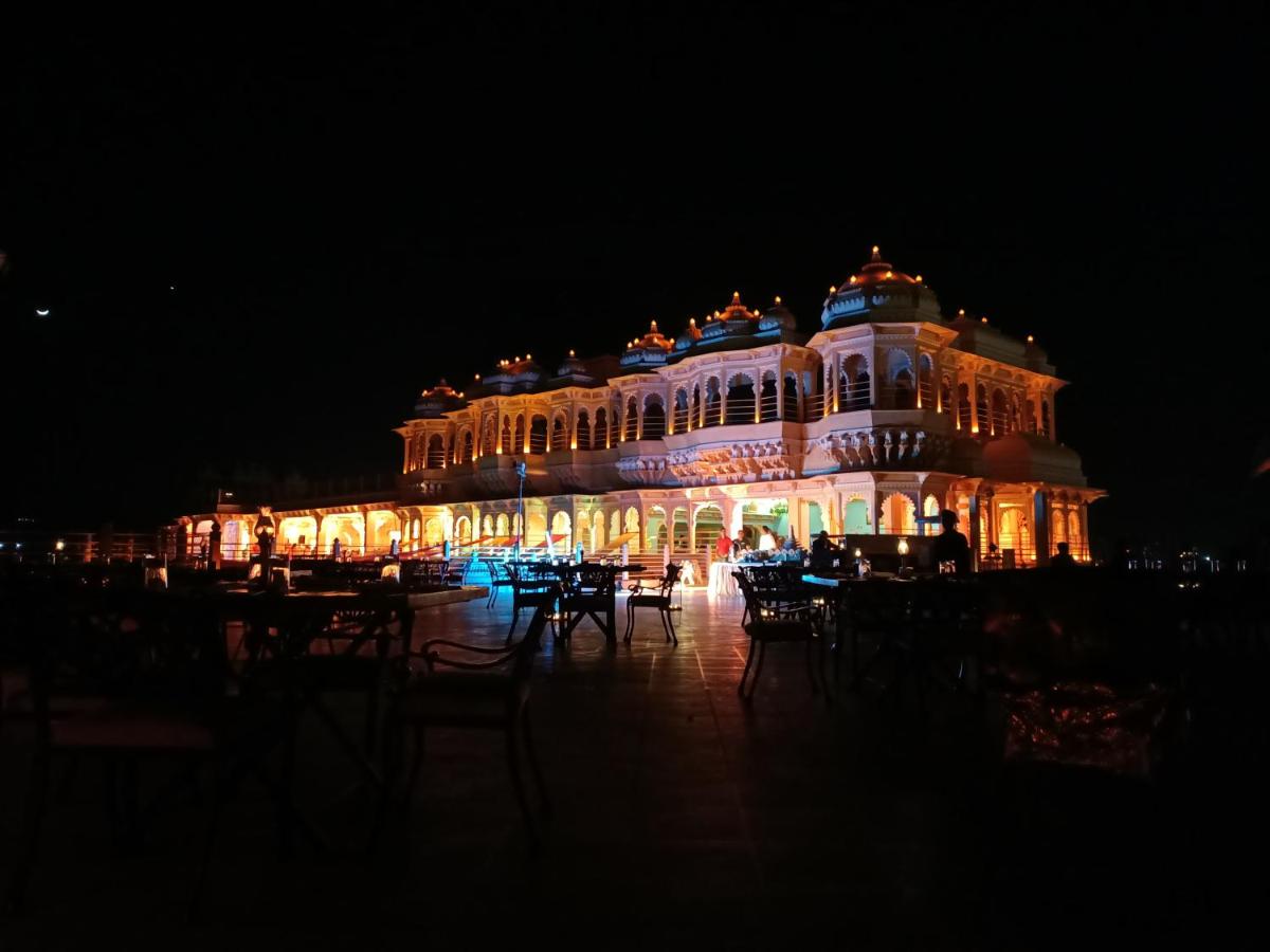 a lit up building with tables and chairs at night at Chunda Palace in Udaipur