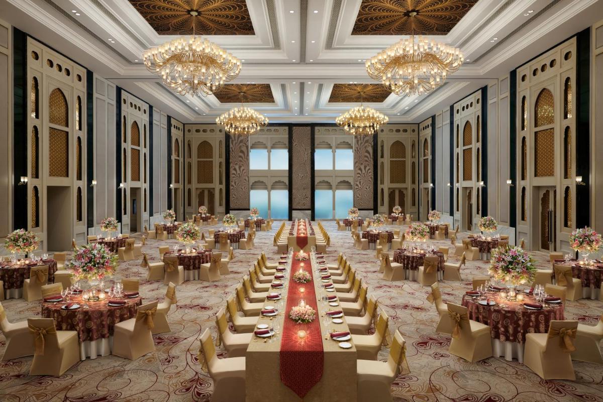 a large banquet hall with tables and chandeliers at The Leela Palace Jaipur in Jaipur