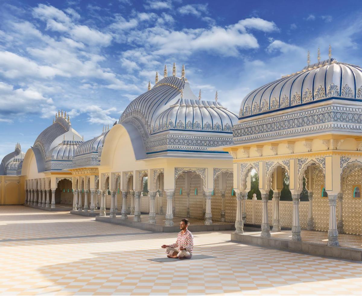 a person sitting on the ground in front of a building at The Leela Palace Jaipur in Jaipur