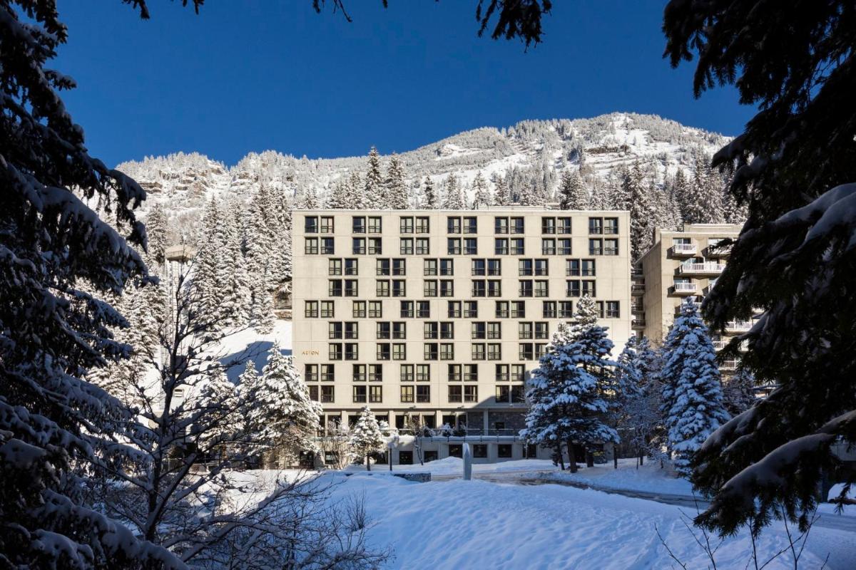 un bâtiment dans la neige avec une montagne en arrière-plan dans l'établissement RockyPop Flaine Hotel & Spa, à Flaine