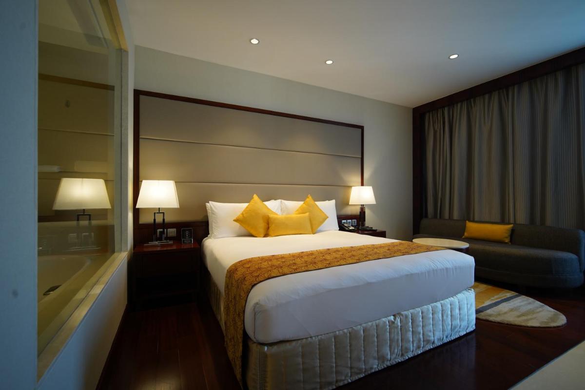a hotel room with a large bed and a couch at Crowne Plaza Kochi by IHG in Cochin