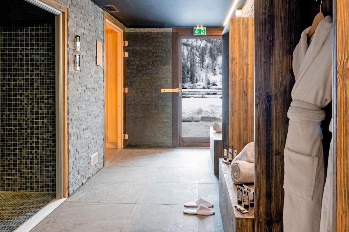 une salle de bain avec une douche à l'italienne et une porte dans l'établissement Hotel Tetras Lodge, à Tignes