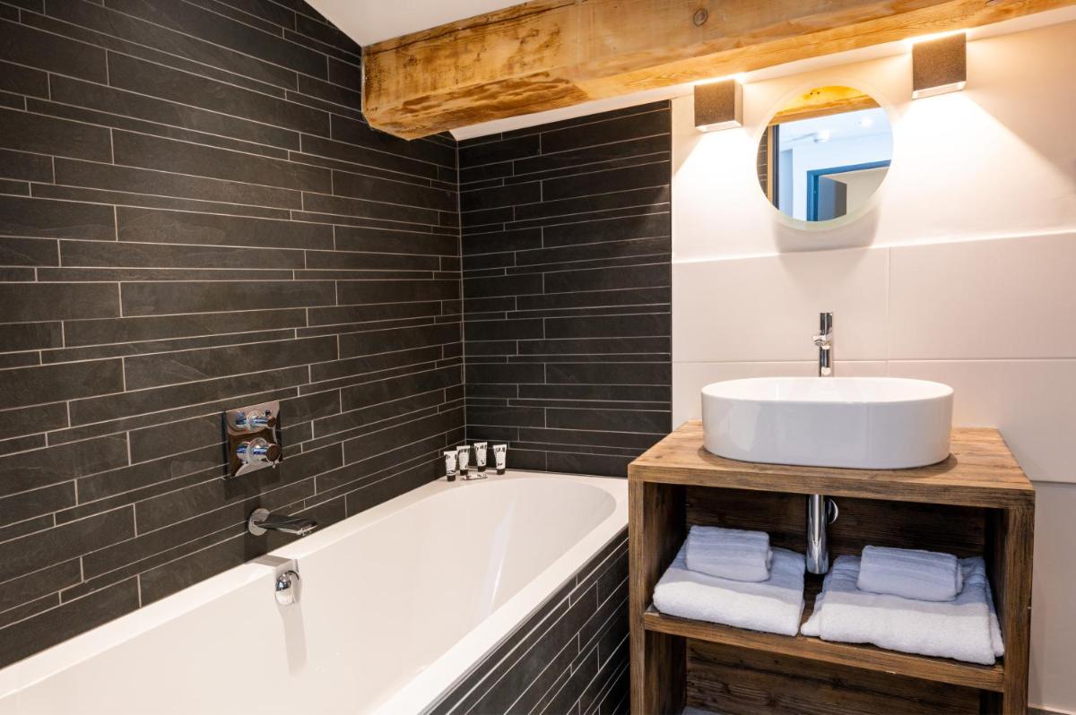une salle de bain avec un lavabo et une baignoire dans l'établissement Hotel Tetras Lodge, à Tignes 22 autres photos