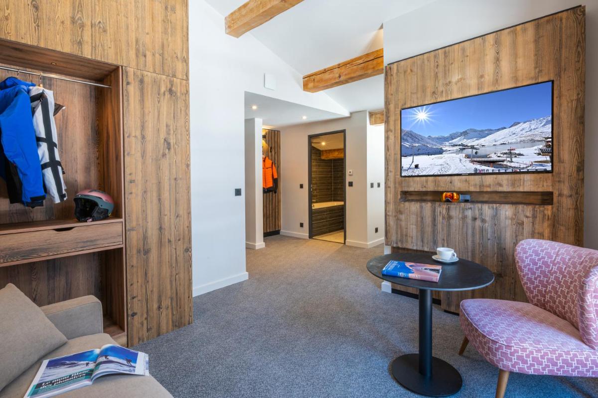 un salon avec une télévision, un canapé et une table dans l'établissement Hotel Tetras Lodge, à Tignes