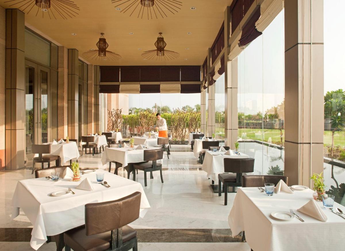 a restaurant with white tables and chairs and windows at Radisson Blu Hotel Amritsar in Amritsar