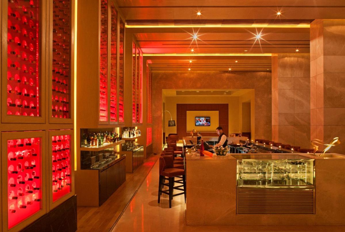 a bar in a restaurant with red wine bottles at Radisson Blu Hotel Amritsar in Amritsar