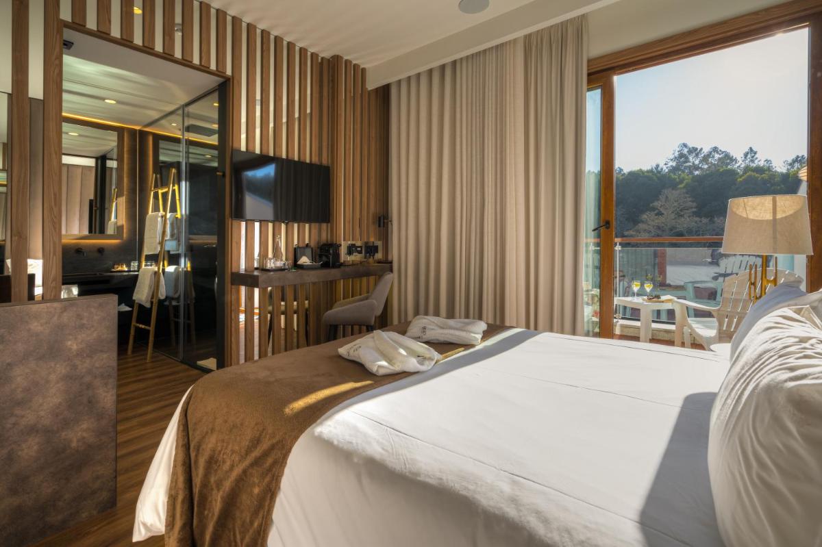 Um quarto com uma cama grande e uma janela ampla. em Hotel Rural Vale Do Rio em Oliveira de Azemeis