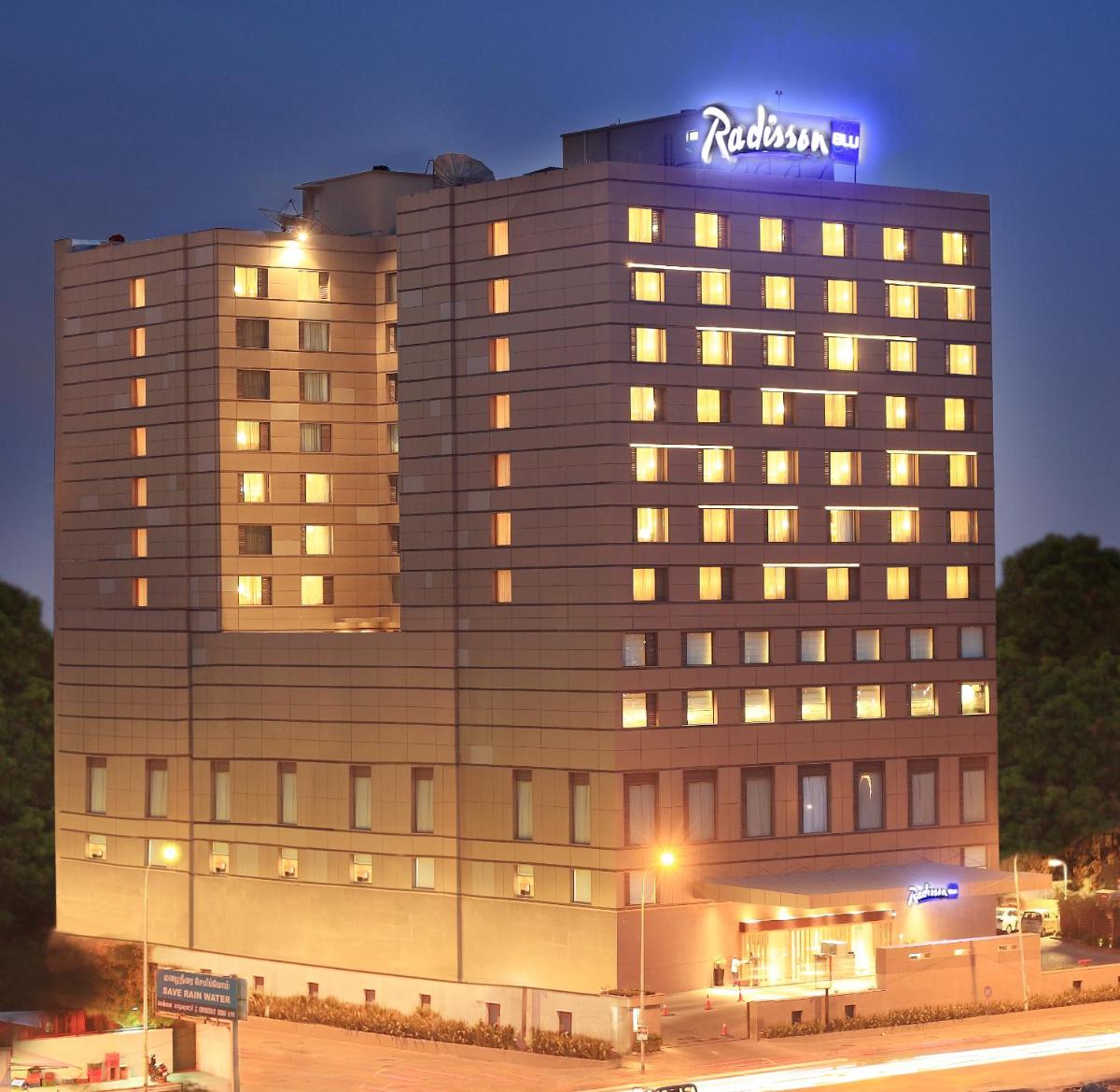 a hotel building with a sign on top of it at Radisson Blu Hotel Chennai City Centre in Chennai a hotel building with a sign on top of it at Radisson Blu Hotel Chennai City Centre in Chennai