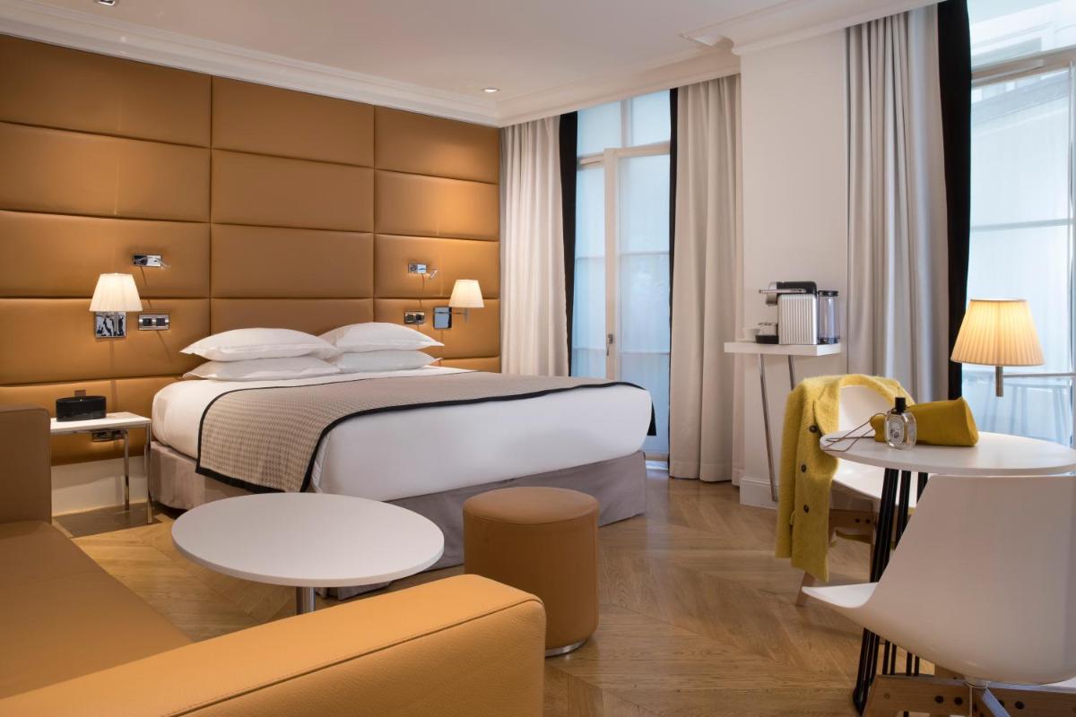 une chambre d'hôtel avec un lit, une table et des chaises dans l'établissement Hôtel R de Paris - Boutique Hotel, à Paris