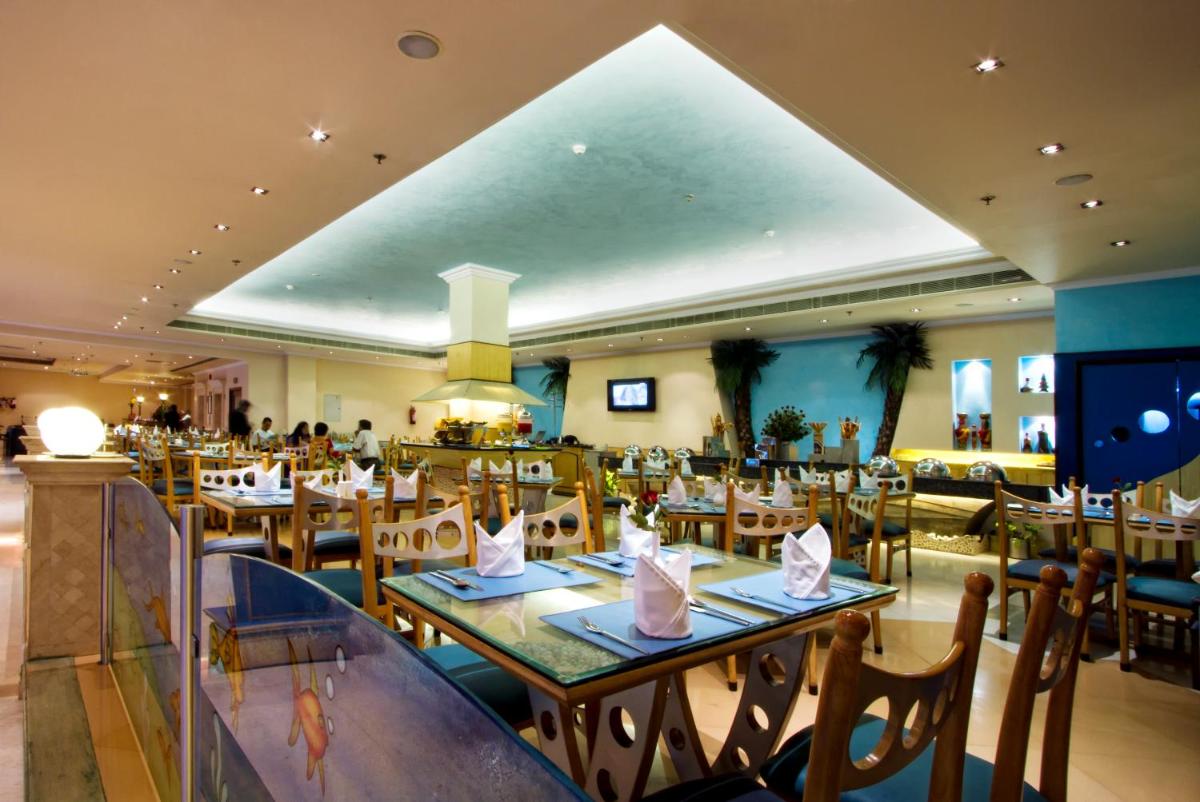 a restaurant with tables and chairs in a room at The Piccadily in Lucknow