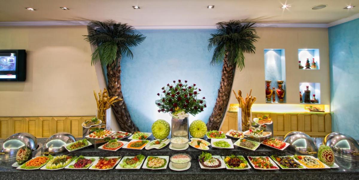 a table full of food with palm trees in the background at The Piccadily in Lucknow