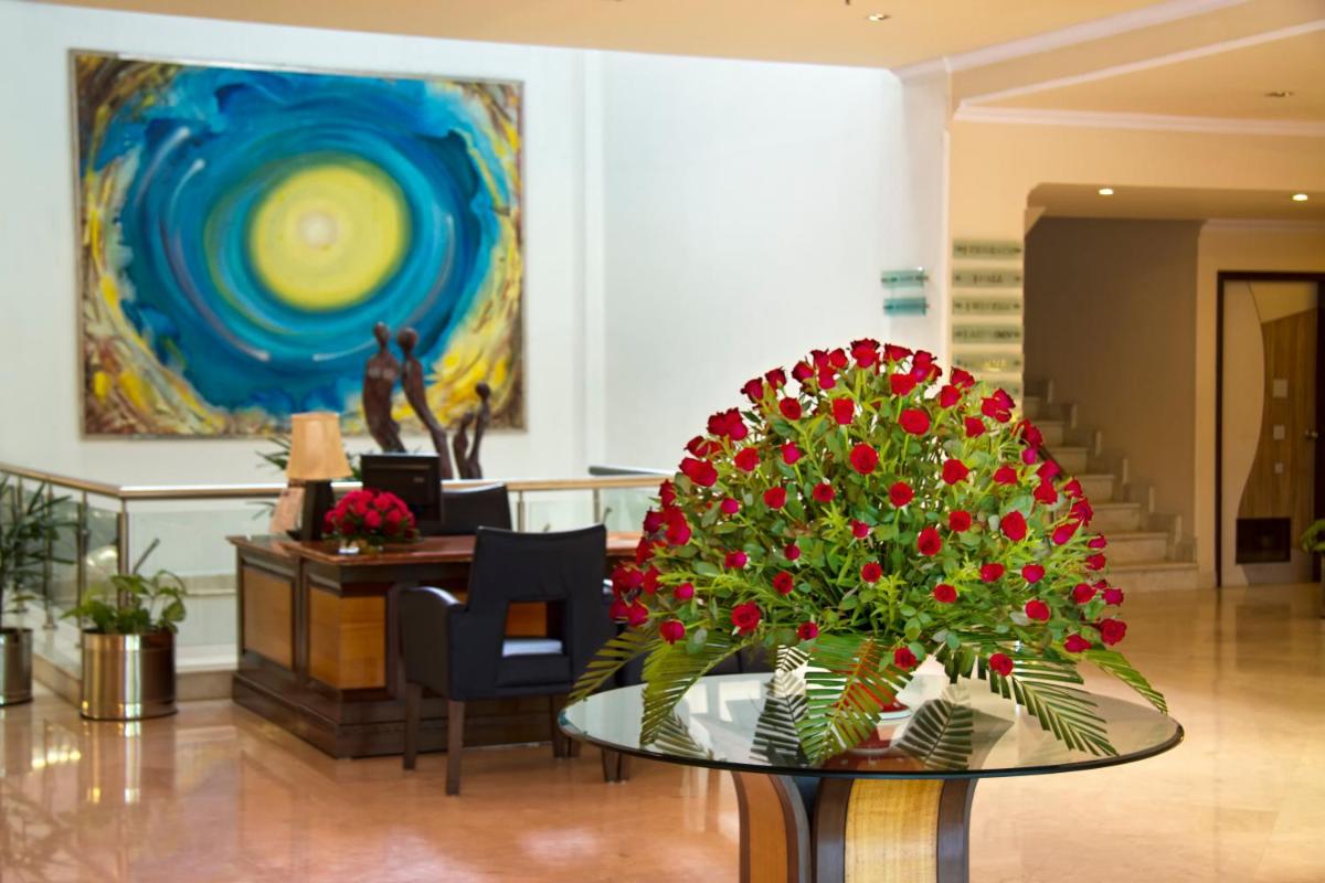 a lobby with a table with red flowers on it at The Piccadily in Lucknow