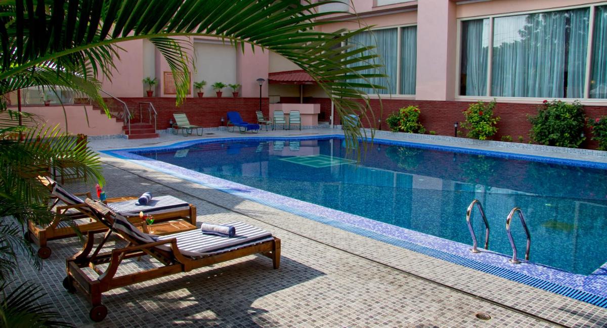 a swimming pool with two lounge chairs next to a building at The Piccadily in Lucknow