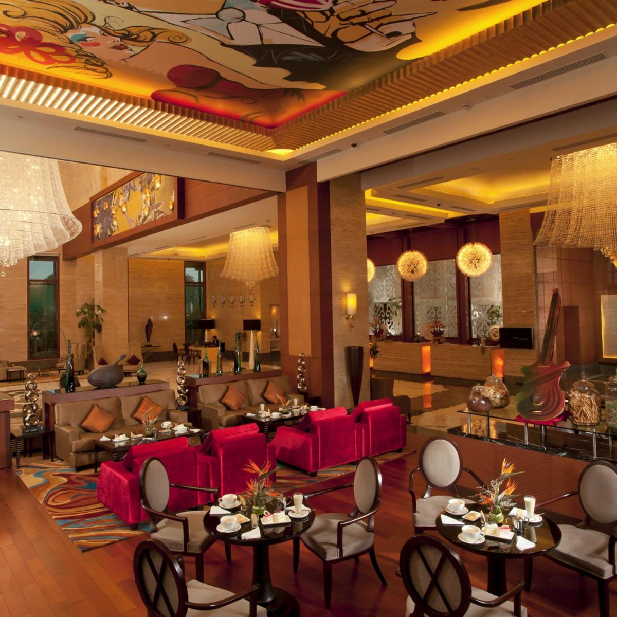 a lobby with red couches and tables and chairs at Radisson Blu Hotel, Nagpur in Nagpur