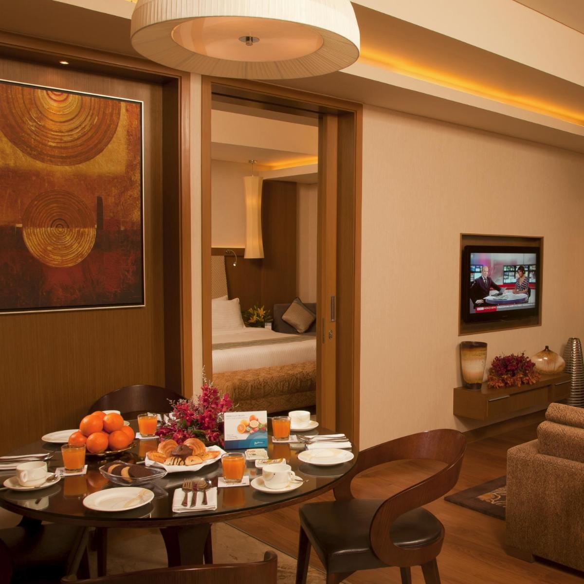 a living room with a table and a bedroom at Radisson Blu Hotel, Nagpur in Nagpur