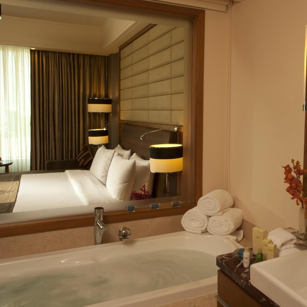 a bathroom with a bed and a bath tub with a mirror at Radisson Blu Hotel, Nagpur in Nagpur