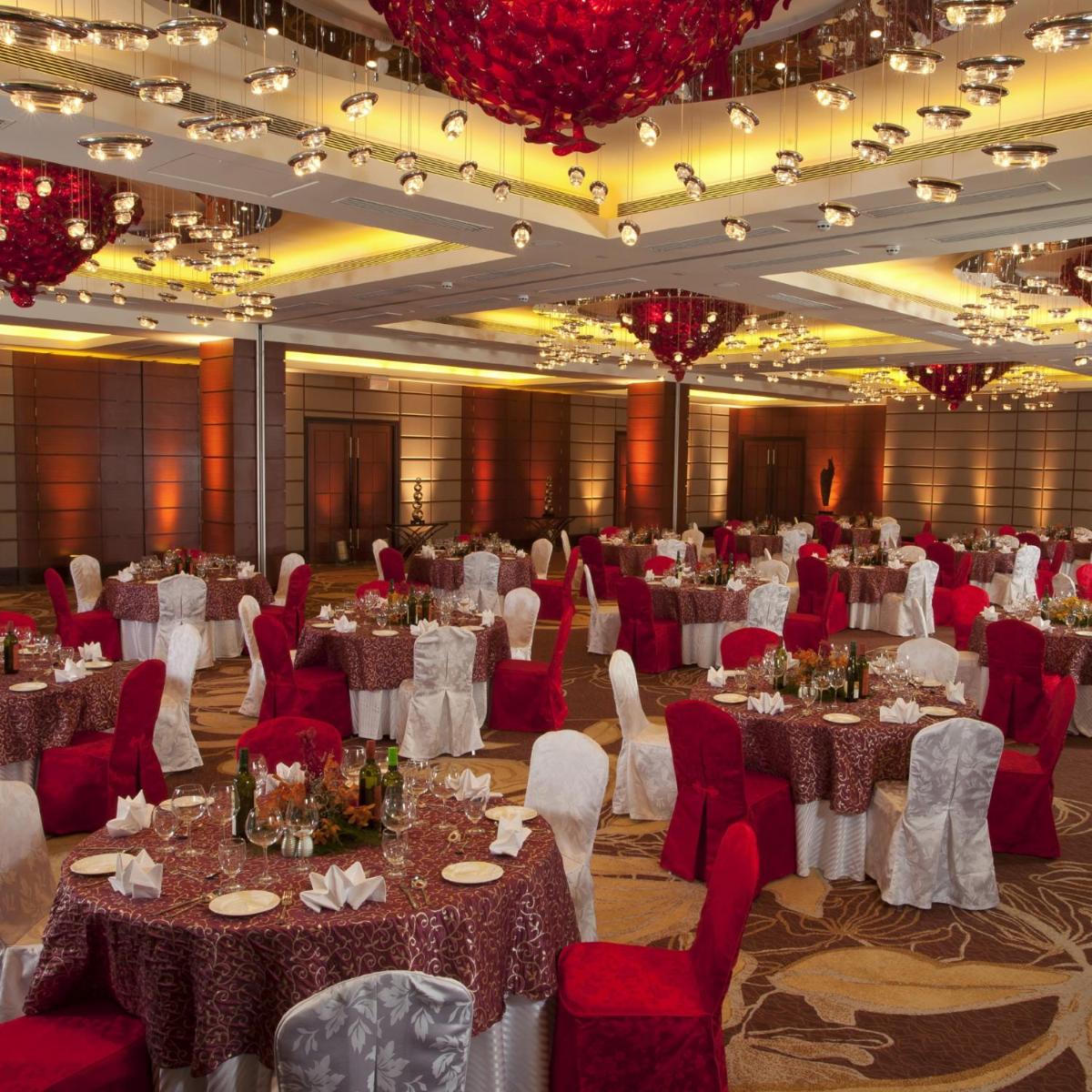 a banquet hall with white tables and red chairs at Radisson Blu Hotel, Nagpur in Nagpur