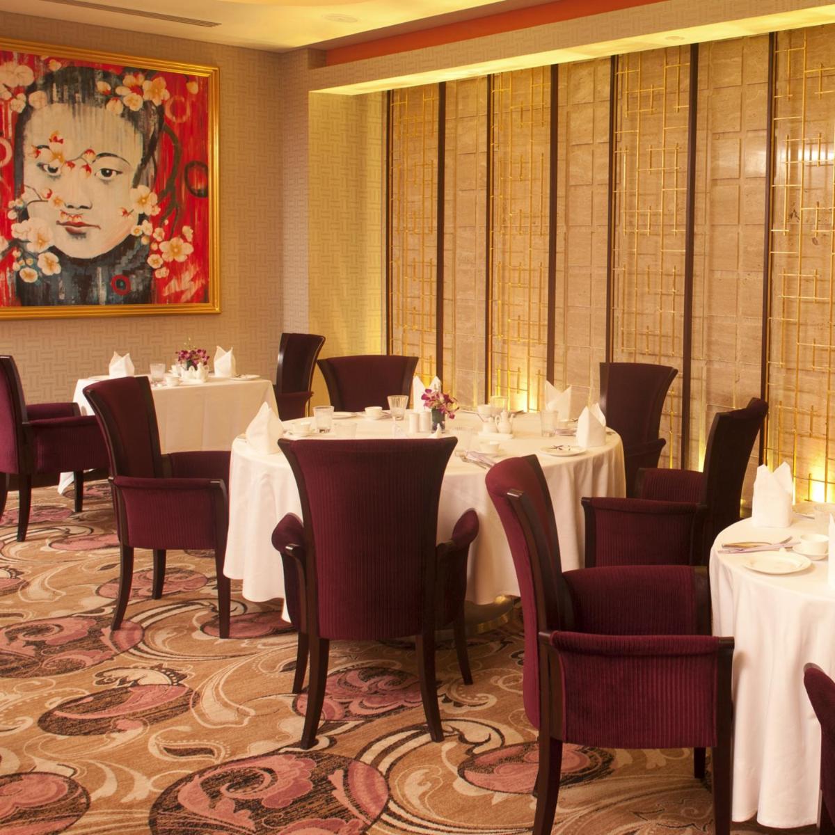 a dining room with tables and chairs and a painting at Radisson Blu Hotel, Nagpur in Nagpur