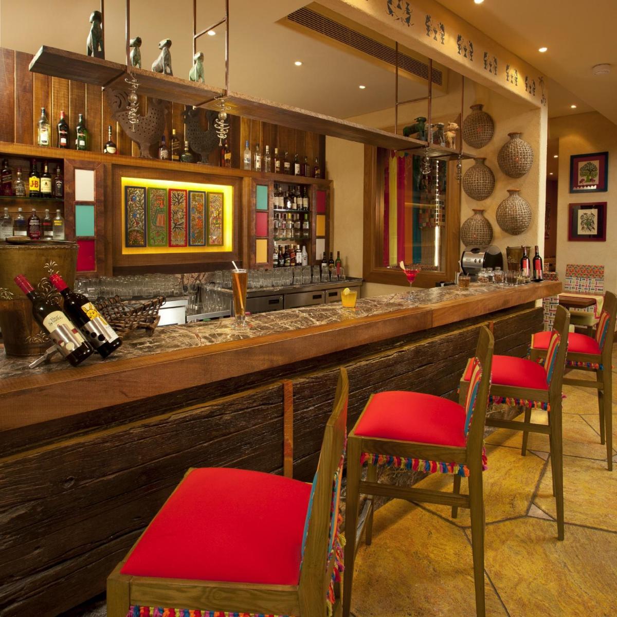 a restaurant with a bar with red chairs at Radisson Blu Hotel, Nagpur in Nagpur