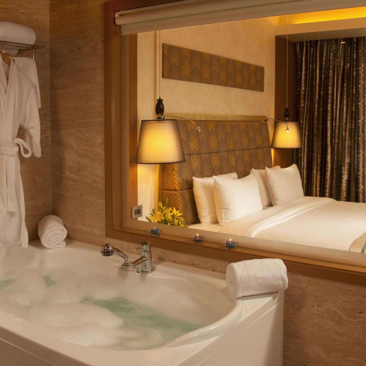a bathroom with a tub and a bed and a mirror at Radisson Blu Hotel, Nagpur in Nagpur