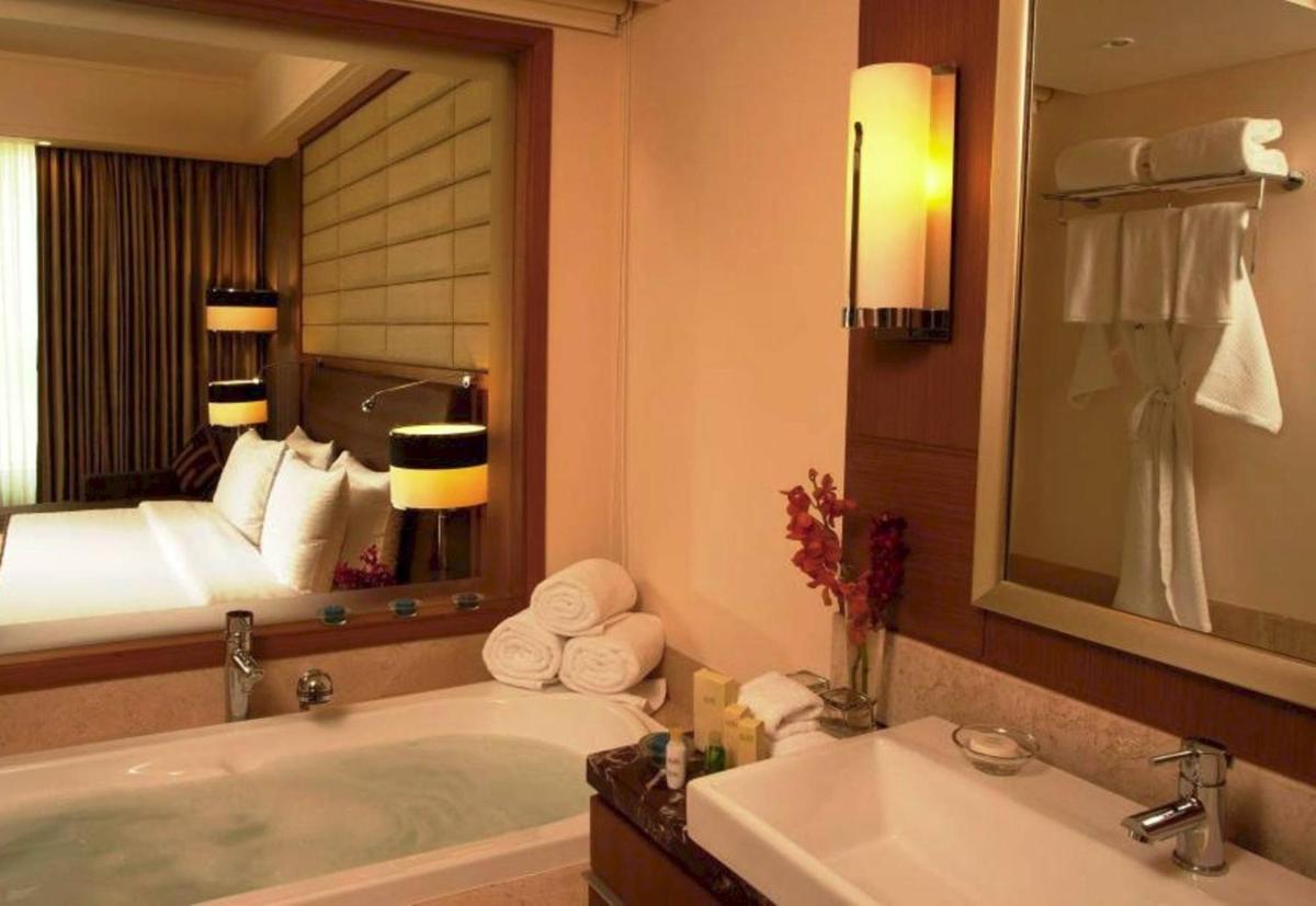a bathroom with a bath tub and a large mirror at Radisson Blu Hotel, Nagpur in Nagpur