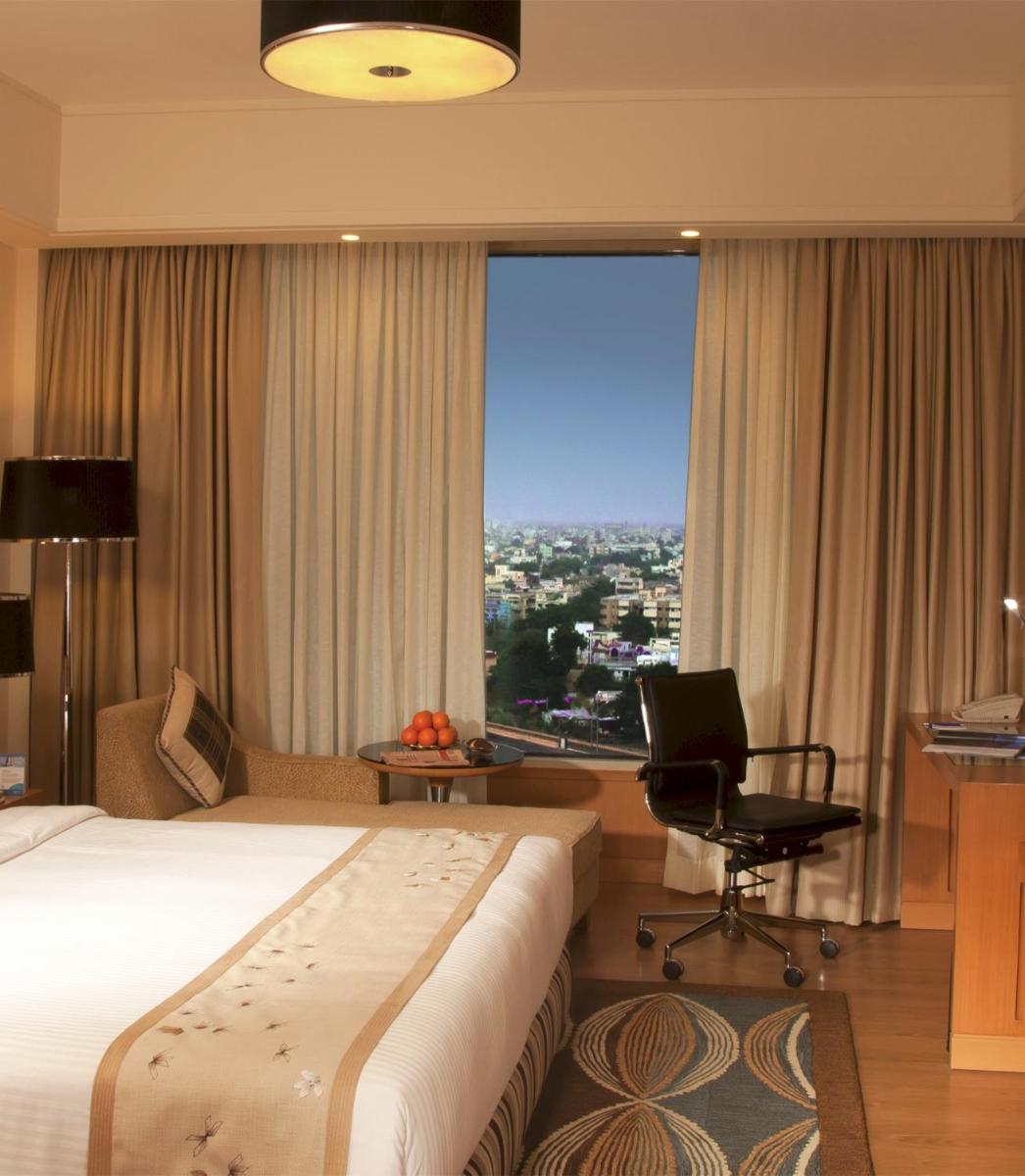 a hotel room with a bed and a chair and a window at Radisson Blu Hotel, Nagpur in Nagpur