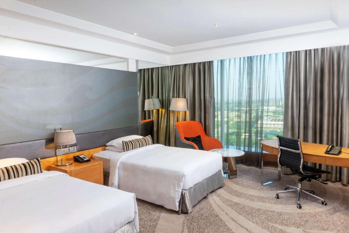a hotel room with two beds and a desk at Hyatt Regency Gurgaon in Gurgaon