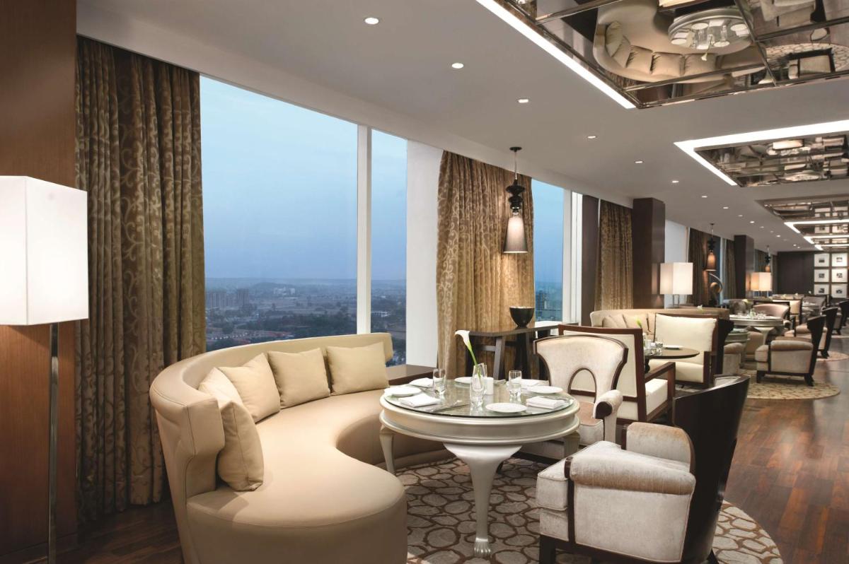 a hotel lobby with a couch and a table and chairs at Hyatt Regency Gurgaon in Gurgaon