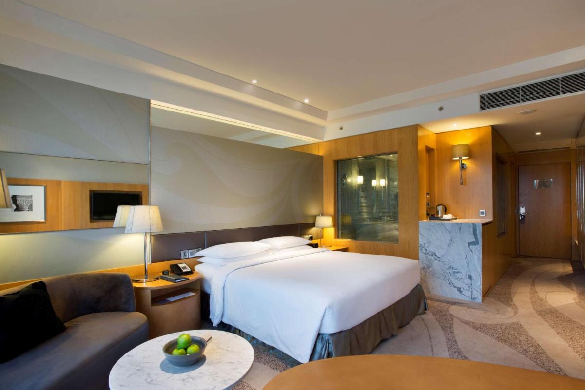 a hotel room with a large bed and a couch at Hyatt Regency Gurgaon in Gurgaon