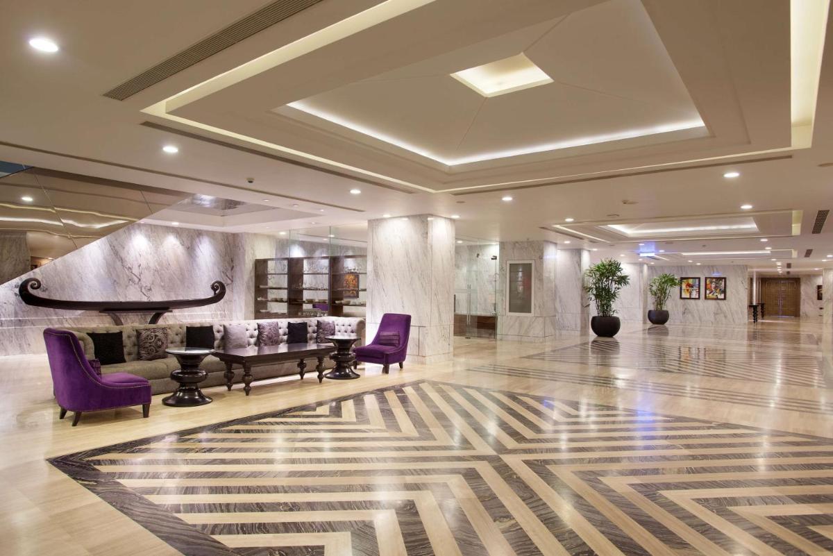 a lobby with purple chairs and a piano at Hyatt Regency Gurgaon in Gurgaon