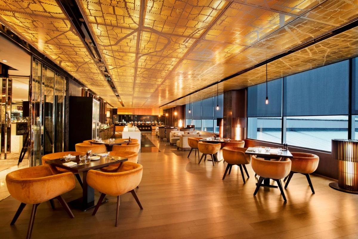 a restaurant with tables and chairs and windows at Hyatt Regency Gurgaon in Gurgaon