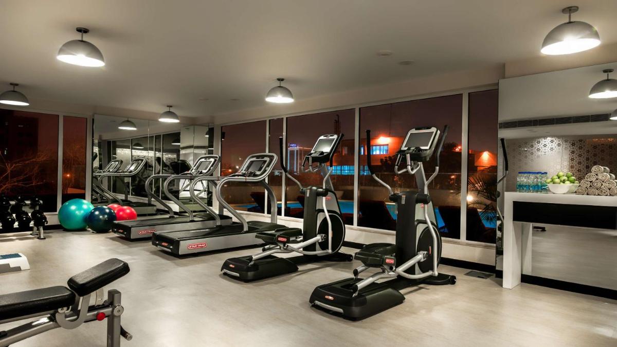 a gym with several treadmills and elliptical machines at Hyatt Place Gurgaon Udyog Vihar in Gurgaon