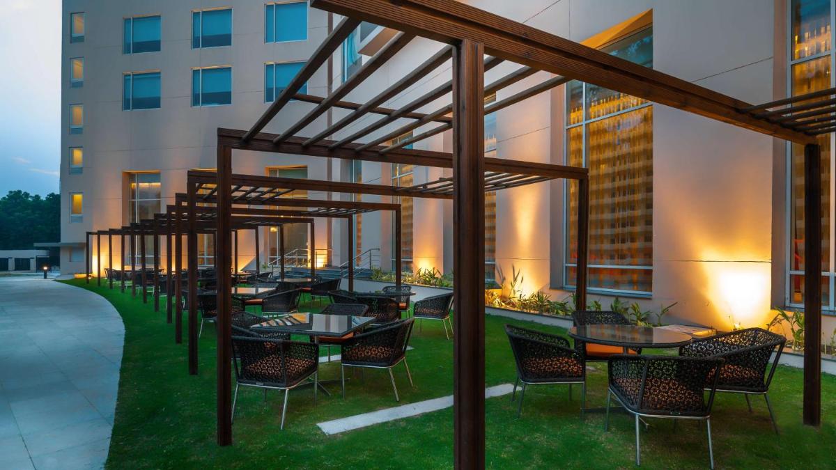 a patio with tables and chairs and a building at Hyatt Place Gurgaon Udyog Vihar in Gurgaon