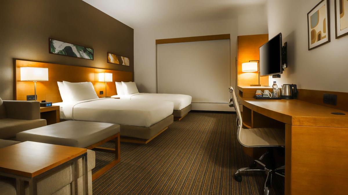 a hotel room with two beds and a desk at Hyatt Place Gurgaon Udyog Vihar in Gurgaon