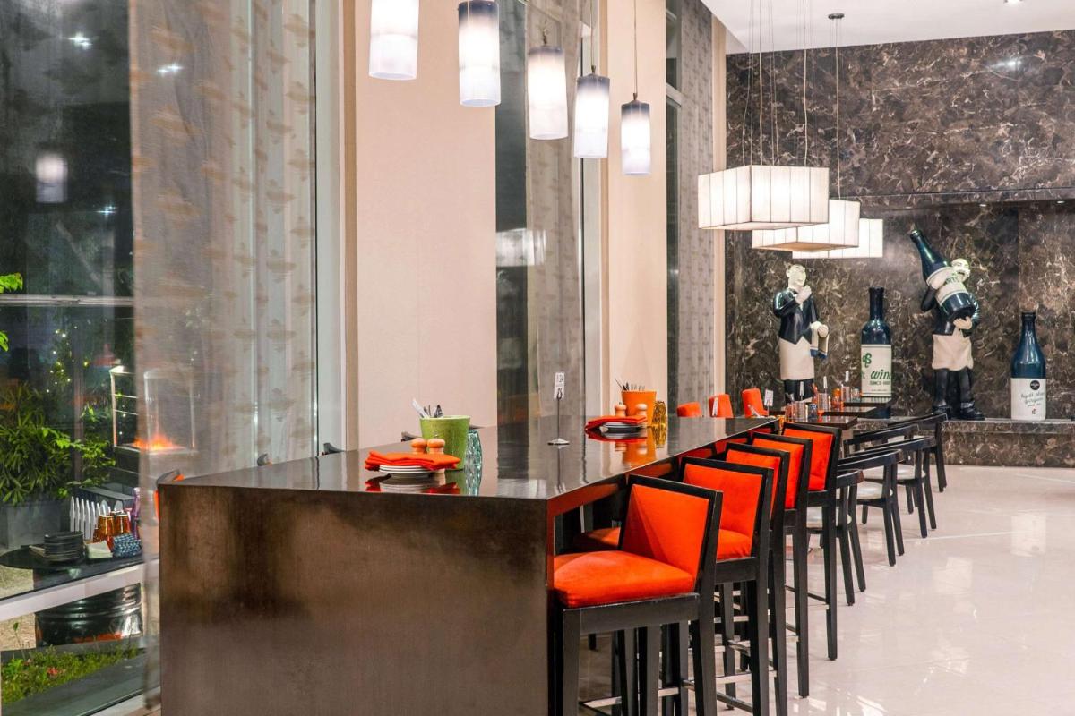 a bar with orange chairs in a restaurant at Hyatt Place Gurgaon Udyog Vihar in Gurgaon