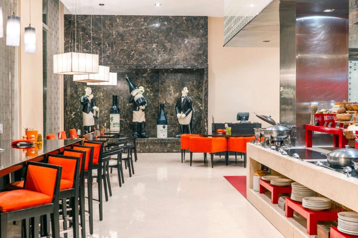 a restaurant with orange chairs and a display of mannequins at Hyatt Place Gurgaon Udyog Vihar in Gurgaon