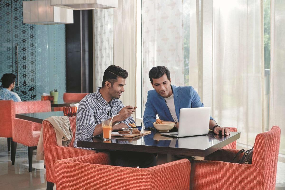 two men sitting at a table with a laptop at Hyatt Place Gurgaon Udyog Vihar in Gurgaon