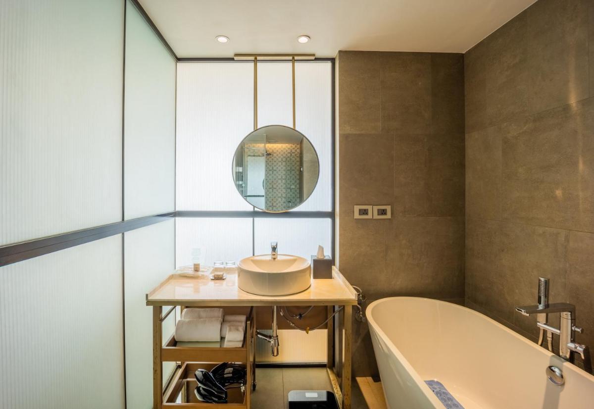 a bathroom with a sink and a tub and a mirror at Holiday Inn Goa Candolim in Candolim a bathroom with a sink and a tub and a mirror at Holiday Inn Goa Candolim in Candolim