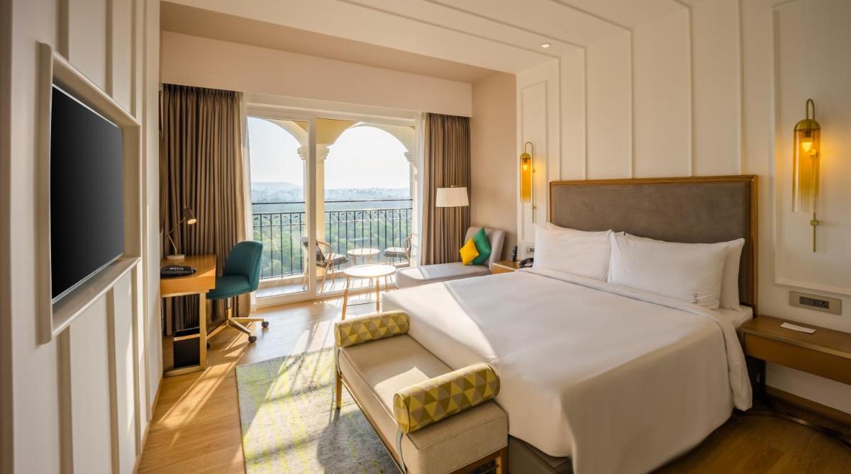 a hotel room with a bed and a balcony at Holiday Inn Goa Candolim in Candolim a hotel room with a bed and a balcony at Holiday Inn Goa Candolim in Candolim
