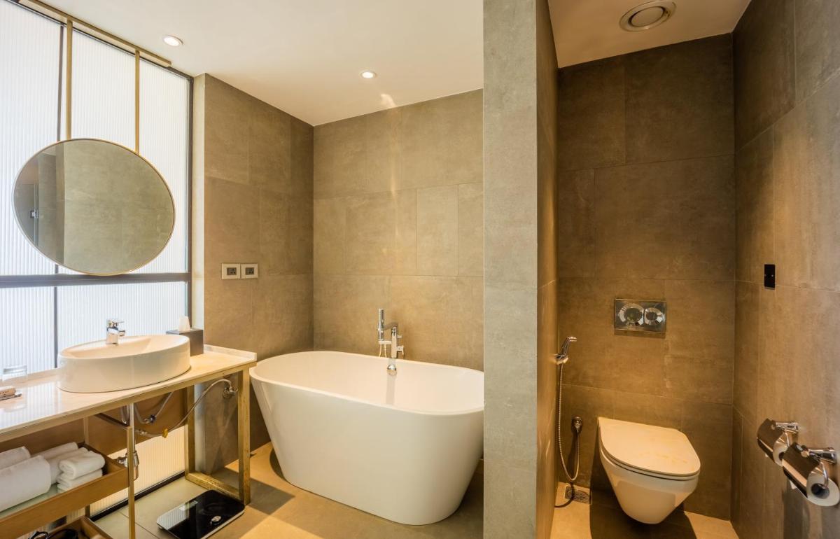 a bathroom with a tub and a sink and a toilet at Holiday Inn Goa Candolim in Candolim a bathroom with a tub and a sink and a toilet at Holiday Inn Goa Candolim in Candolim