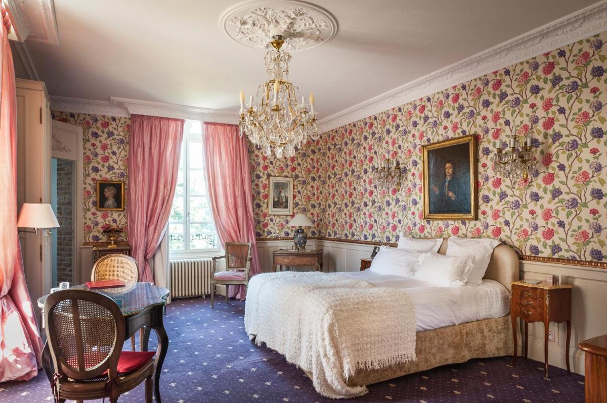 une chambre avec un lit et un lustre dans l'établissement Château D'Apigné Rennes, à Le Rheu une chambre avec un lit et un lustre dans l'établissement Château D'Apigné Rennes, à Le Rheu
