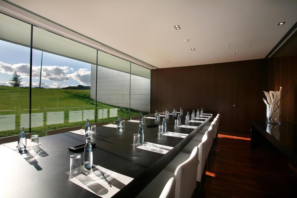 un comedor grande con una mesa larga con sillas blancas en Finca Prats Hotel Golf & Spa, en Lleida