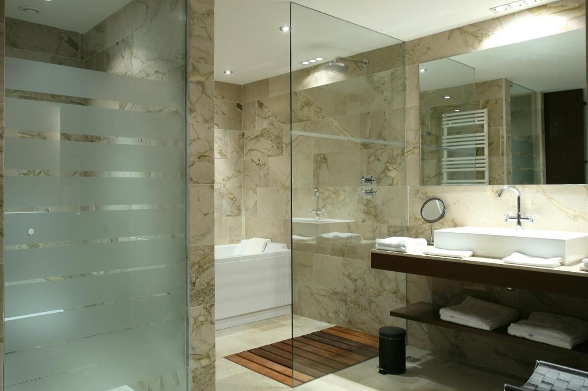 Un baño con ducha, lavabo y espejo. en Finca Prats Hotel Golf & Spa, en Lleida