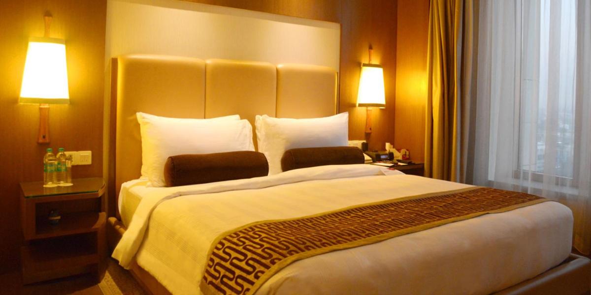 a large bed in a hotel room with two lamps at Crowne Plaza New Delhi Okhla by IHG in New Delhi