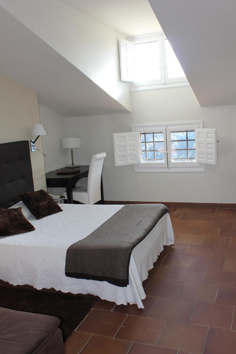 Un dormitorio con una cama y una mesa y ventanas. en Hotel Leonor de Aquitania, en Cuenca
