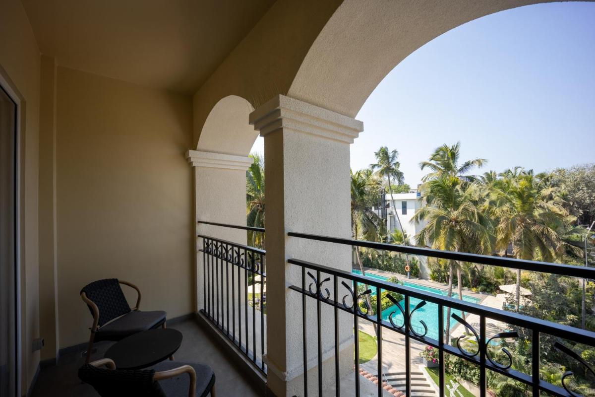 a balcony with a view of a pool and palm trees at Holiday Inn Goa Candolim in Candolim a balcony with a view of a pool and palm trees at Holiday Inn Goa Candolim in Candolim