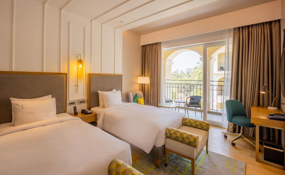 a hotel room with two beds and a balcony at Holiday Inn Goa Candolim in Candolim a hotel room with two beds and a balcony at Holiday Inn Goa Candolim in Candolim